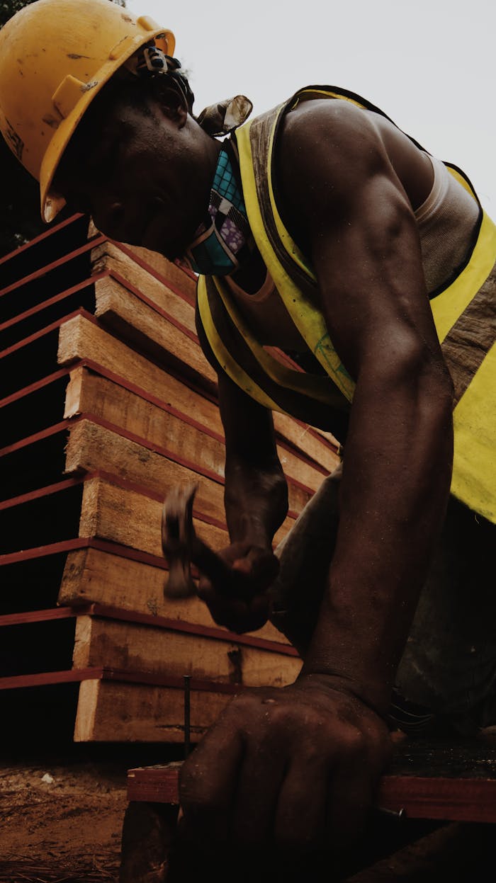 From below of African American man in helmet with hammer building house at work